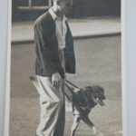 Image is an old sepia phtot of Michael Groombridge walkign with a dog