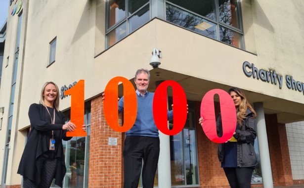 Photo of three of Beacon’s Engagement team, Becky on the left with blond hair, Pete in the middle and Meena on the right with long dark hair. They are outside the Beacon Centre holding up large perspex numbers which spell out 1000.