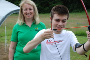 Volunteer Liz with Lee, who has been supported by Sight for Surrey since he was three years old, trying his hand at archery.