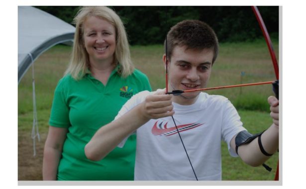 Volunteer Liz with Lee Roake, who has been supported by Sight for Surrey since he was three years old, trying his hand at archery.