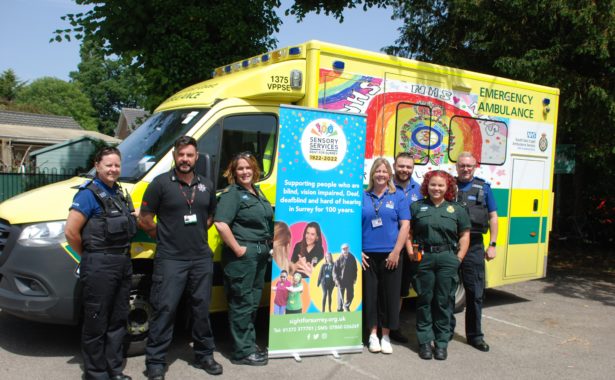 Team 999 BSL (Surrey Police, Surrey Fire & Rescue & South East Coast Ambulance Service and Sight for Surrey staff) standing in front of an ambulance on either side of a Sight for Surrey banner.