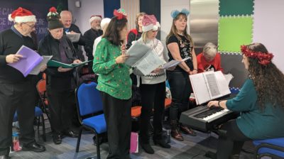 Choir in full swing wearing festive hats and head gear.