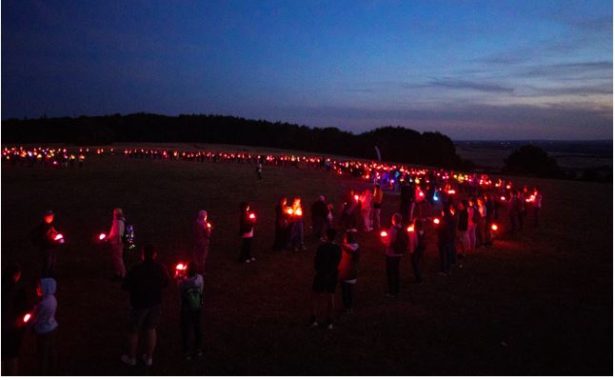 Pretty lights against the night sky created by a crowd of people on Dunstable Downs at night holding Geolights.