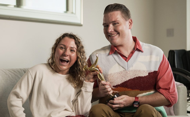 Ella (Emily Nicole Roberts) and Sam (Jake Sawyers) holding a trophy in comedy The i-Word.