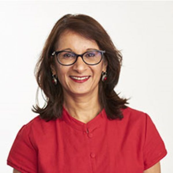 Shahina smiling, wearing a red top and glasses.
