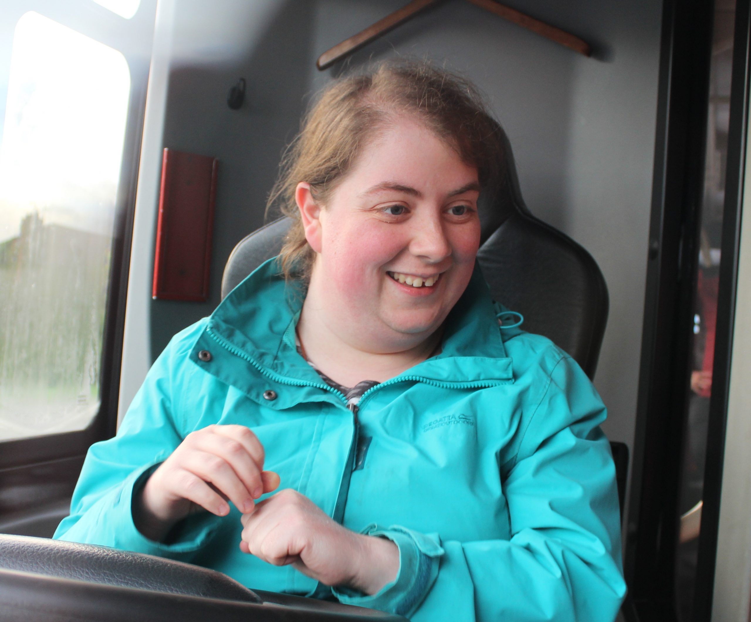 Kellie smiling, wearing a turquoise jacket.
