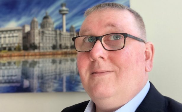 Pete Hoey with photo of a building reflected in water in the background.