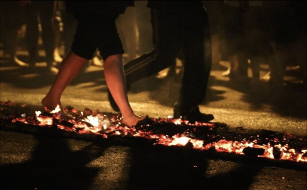 A person walking bare foot along burning coals and embers.