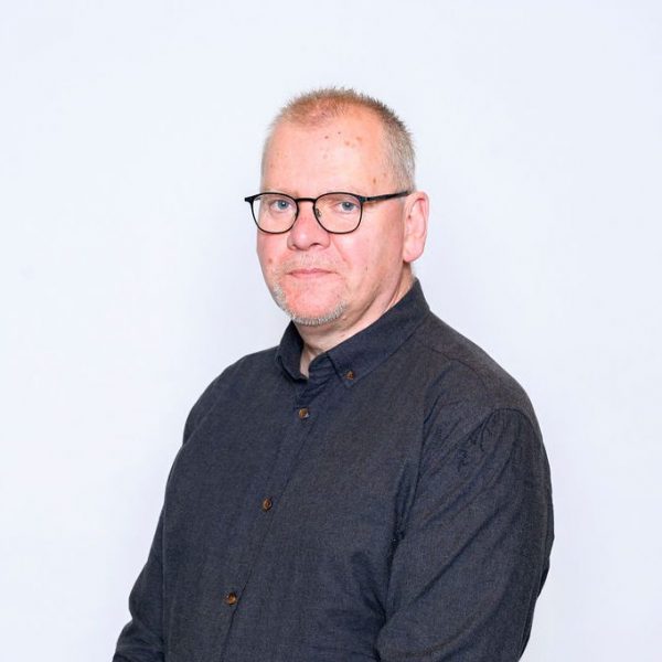 Keith Eales sitting sideways, smiling wearing a black shirt