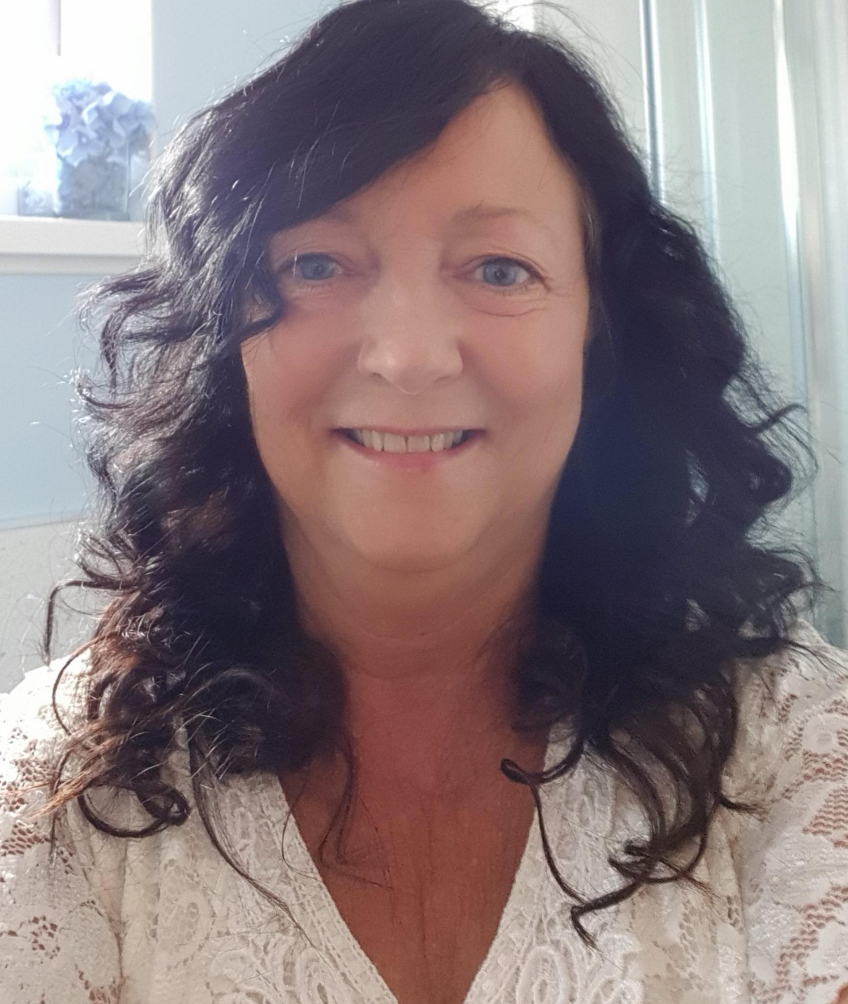 Lorraine Middleton smiling, wearing a white lace top.