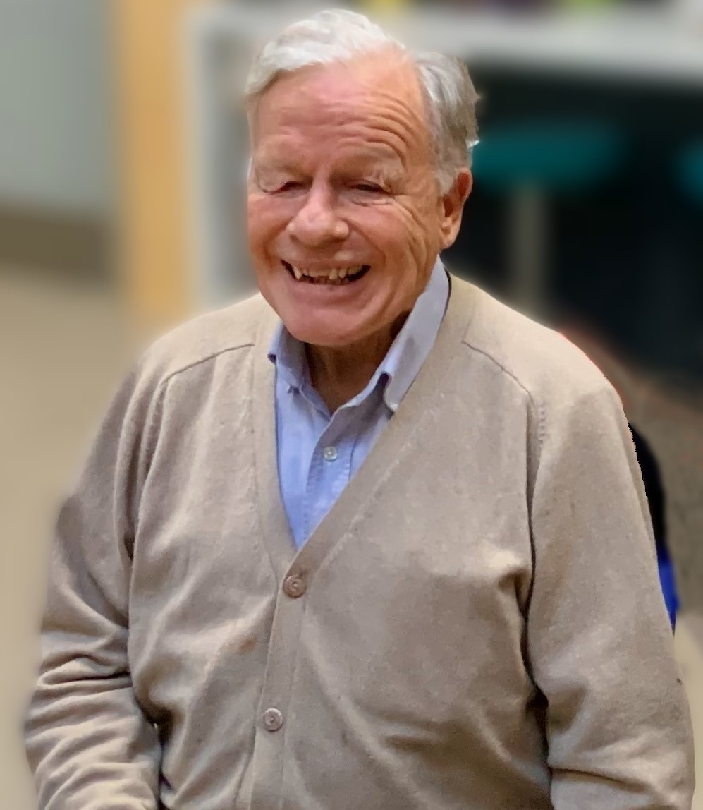 Mike Townsend with a big, warm smile, wearing a blue shirt and beige cardigan.