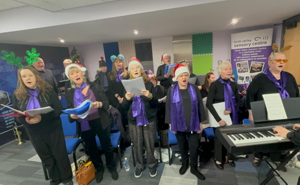 Sensory Singers choir performing, dressed in festive santa hats and headbands and accompanied by a keyboard.