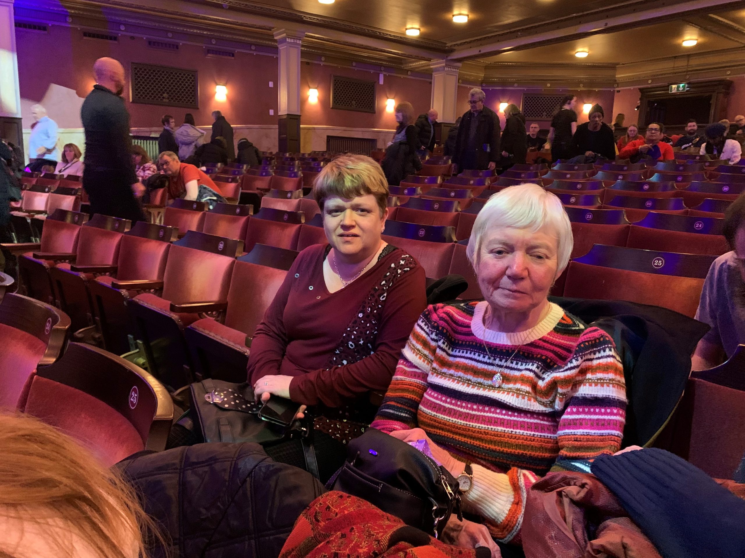 Two women sitting in a theatre during a trip to see a pantomime.