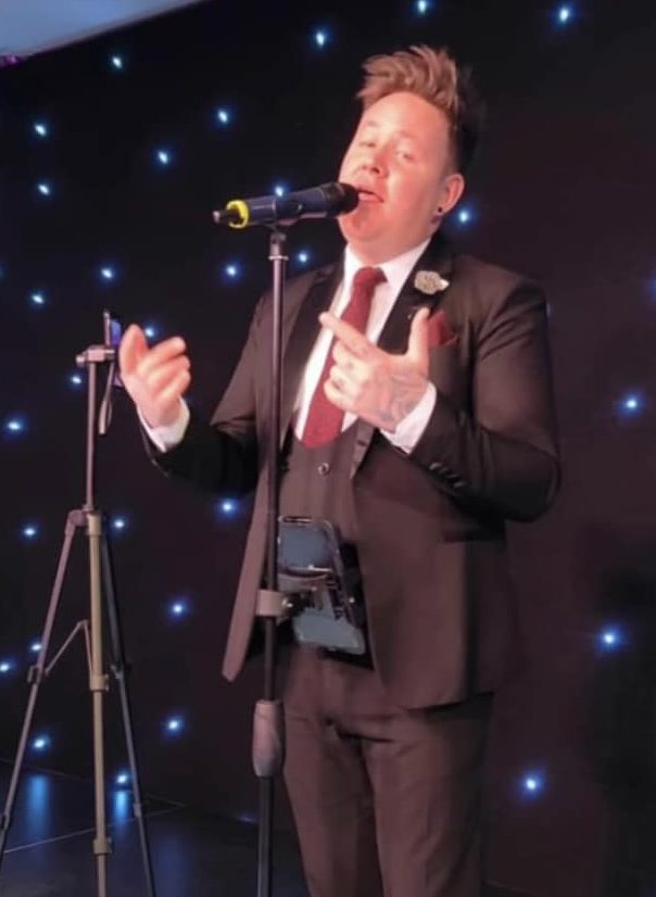 Paul Black singing on stage wearing a 3 piece suit. Photo courtesy of Paul Black.