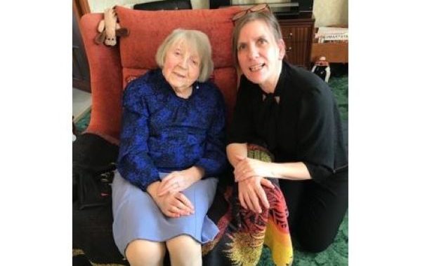 Aileen Gourlay from Dundee sitting in an arm chair and NESS's Gill Sutherland kneeling beside her.