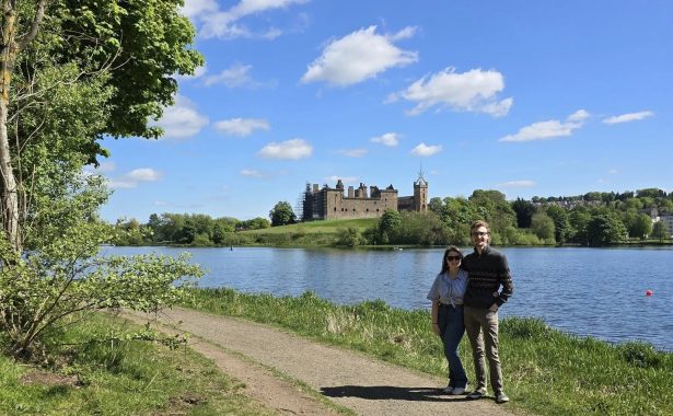 Melissa, FVSC Youth and Family Support Worker with her fiance Michael walking at Linlithgow Loch on a sunny day. Linlithgow Castle is in the distance across the loch.