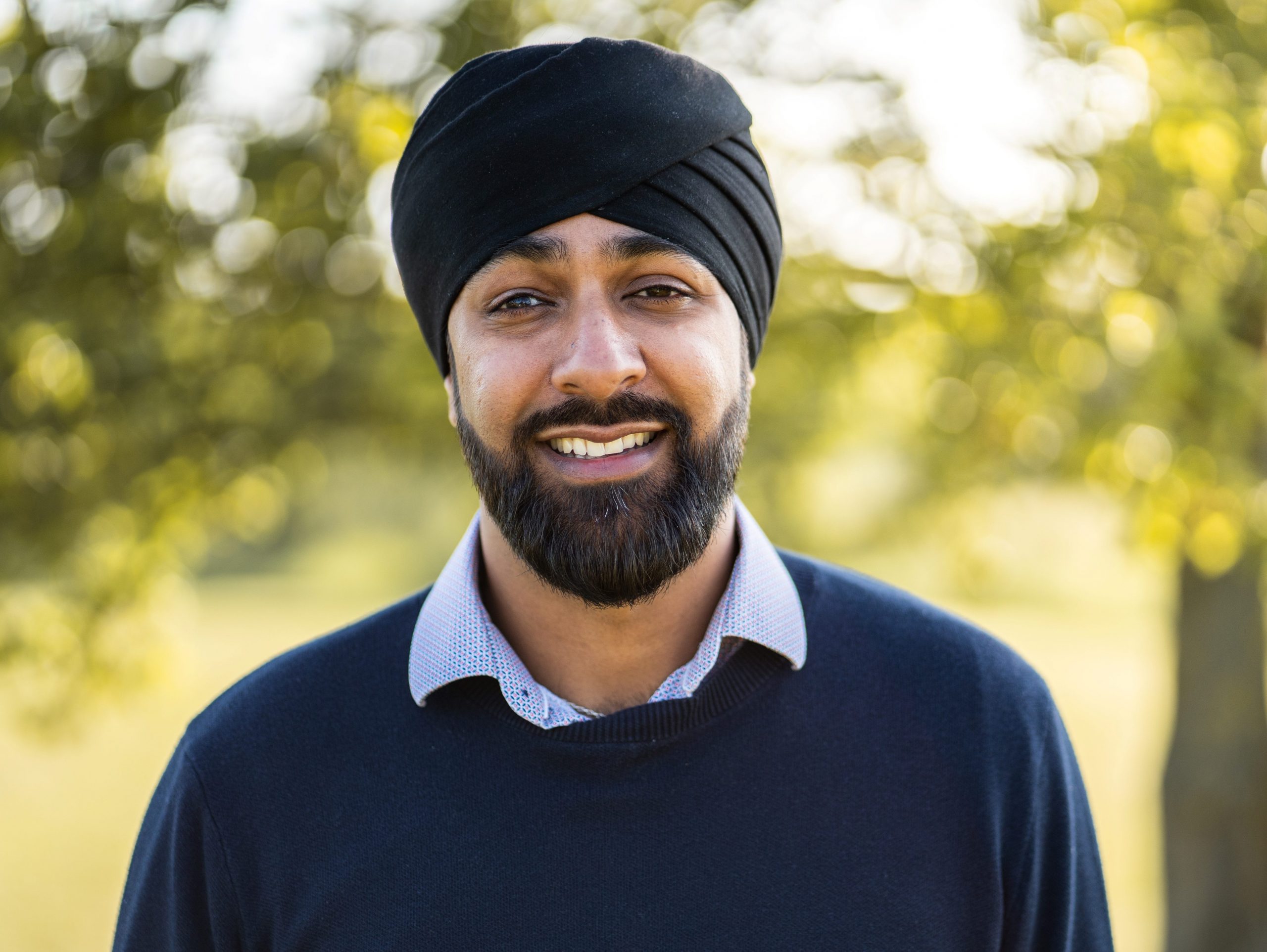 Amit, a turban wearing Sikh man, standing in front of trees. Amit, a turban wearing Sikh man, standing in front of trees.