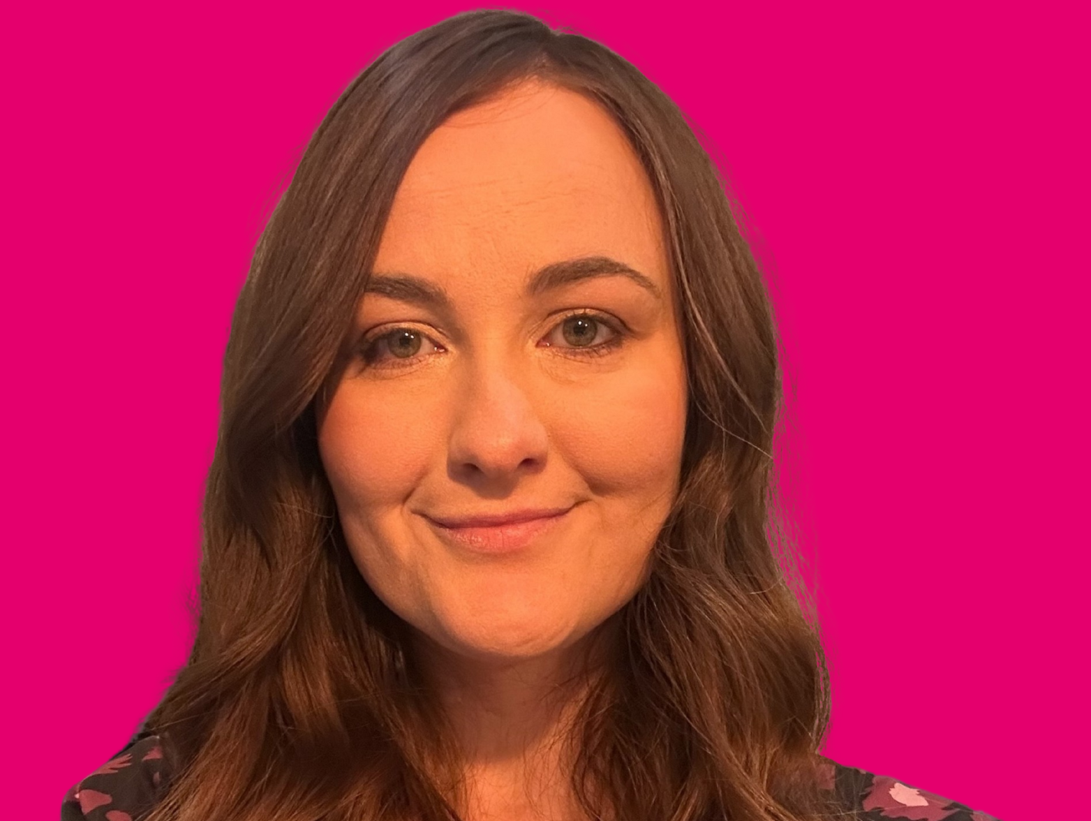 Head and shoulders portrait of Helen Donkin, a woman with long wavy brown hair and fair skin, looking directly at the camera with a gentle smile. She is wearing a dark blouse with a pink floral pattern. The background is a flat, bright magenta colour Head and shoulders portrait of Helen Donkin, a woman with long wavy brown hair and fair skin, looking directly at the camera with a gentle smile. She is wearing a dark blouse with a pink floral pattern. The background is a flat, bright magenta colour
