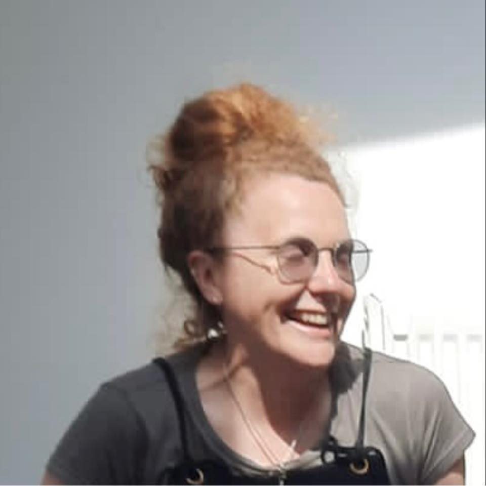 Sarah has red hair and is wearing earrings, glasses and a grey T-shirt. She is laughing. Sarah has red hair and is wearing earrings, glasses and a grey T-shirt. She is laughing.