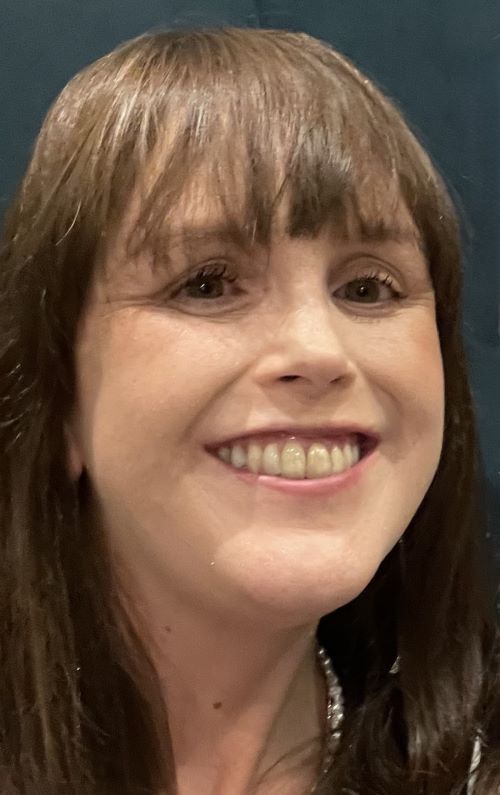 Nia Greer smiling has brunette hair with a fringe.