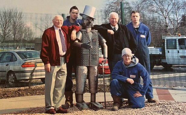 Douglas the Tin Man on installation in the sensory garden, with Tom Binnie (left) and Ian Cruickshanks leaning on his shoulders and two apprentices who helped build him standing behind the sculpture, with another apprentice kneeling in front.