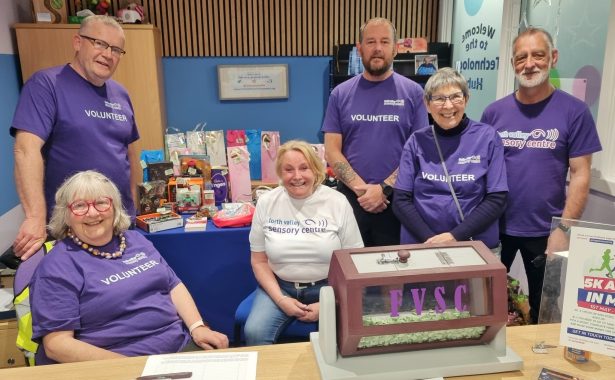 A group photograph shows (left to right) volunteers behind a desk who are wearing Forth Valley Sensory Centre T-shirts: John Somerville, Christine Fraser, Jenn Pow, Duncan McPhee, Ann McFarlane, and Colin Watterson.