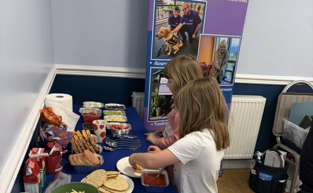 two young girls making their own pizzas from the ingredients laid out.