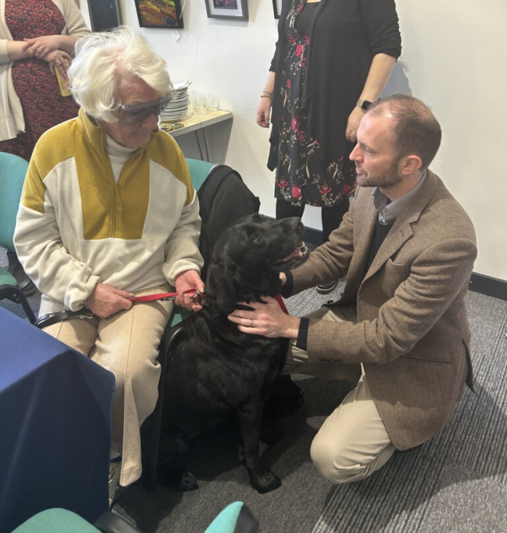 Stephen Gethins MP with a NESS service user patting her black dog.