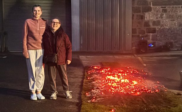 YPSS member Talijah Reinholde and NESS added value services manager Sheila Ogden standing together smiling, to the left of the firewalk coals.