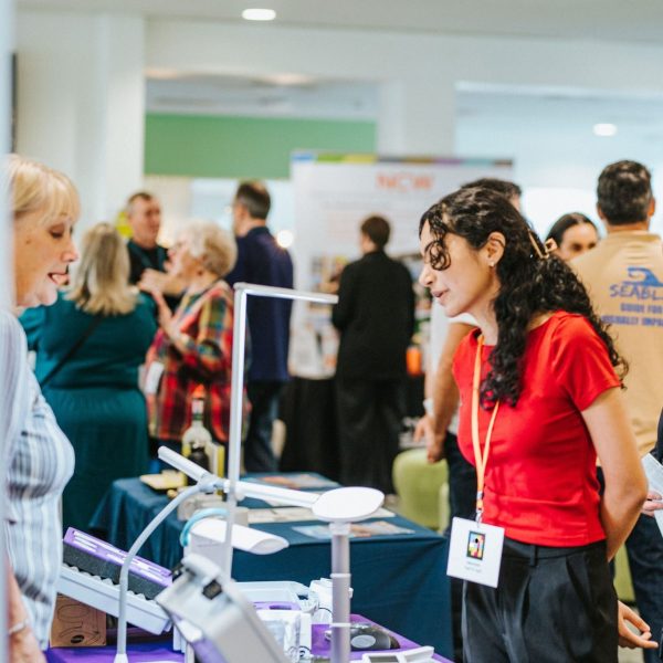The 2025 exhibition, at forefront is a delegate looking at a stand and speaking to an exhibitor