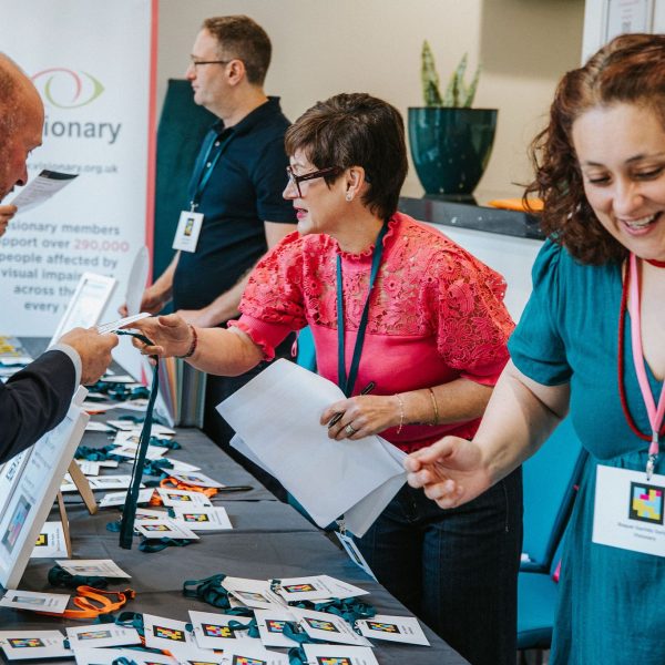 The registration desk at the 2025 conference, Member of the Visionary conference team are talking to delegates as they arrive, having over badges and information