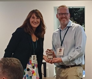 Kerry Bevan from Guide Dogs smiling next to Andy Smith MyVision Oxfordshire who is holding a trophy.